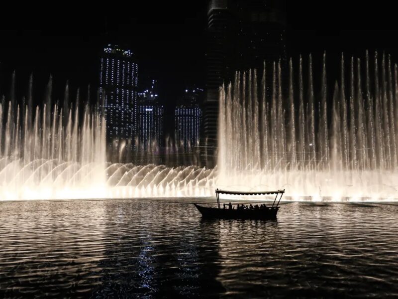 The Dubai Fountain at night in Downtown Dubai with a boat on Burj Lake